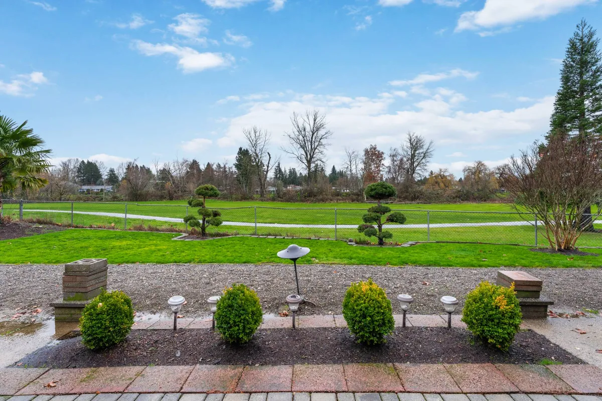 A peaceful view of a manicured lawn bordered by decorative shrubs and a pathway, evoking a sense of outdoor calm and relaxation. The open lawn could represent the golf course or be a setting for enjoying the tranquil ambiance described in the section.