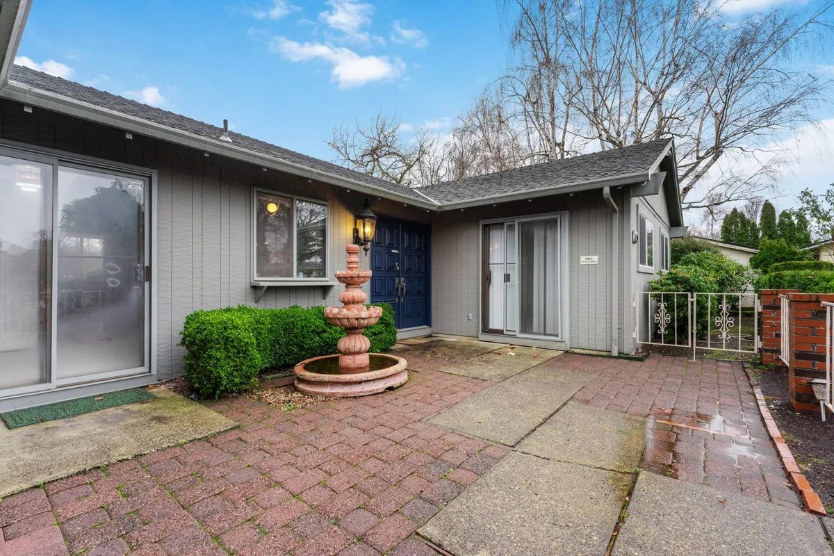 The exterior of Golfview Ranch features a welcoming blue door framed by green shrubs and a charming water fountain along a brick pathway. The scene sets an inviting tone, suggesting a warm homecoming after days spent exploring the region.