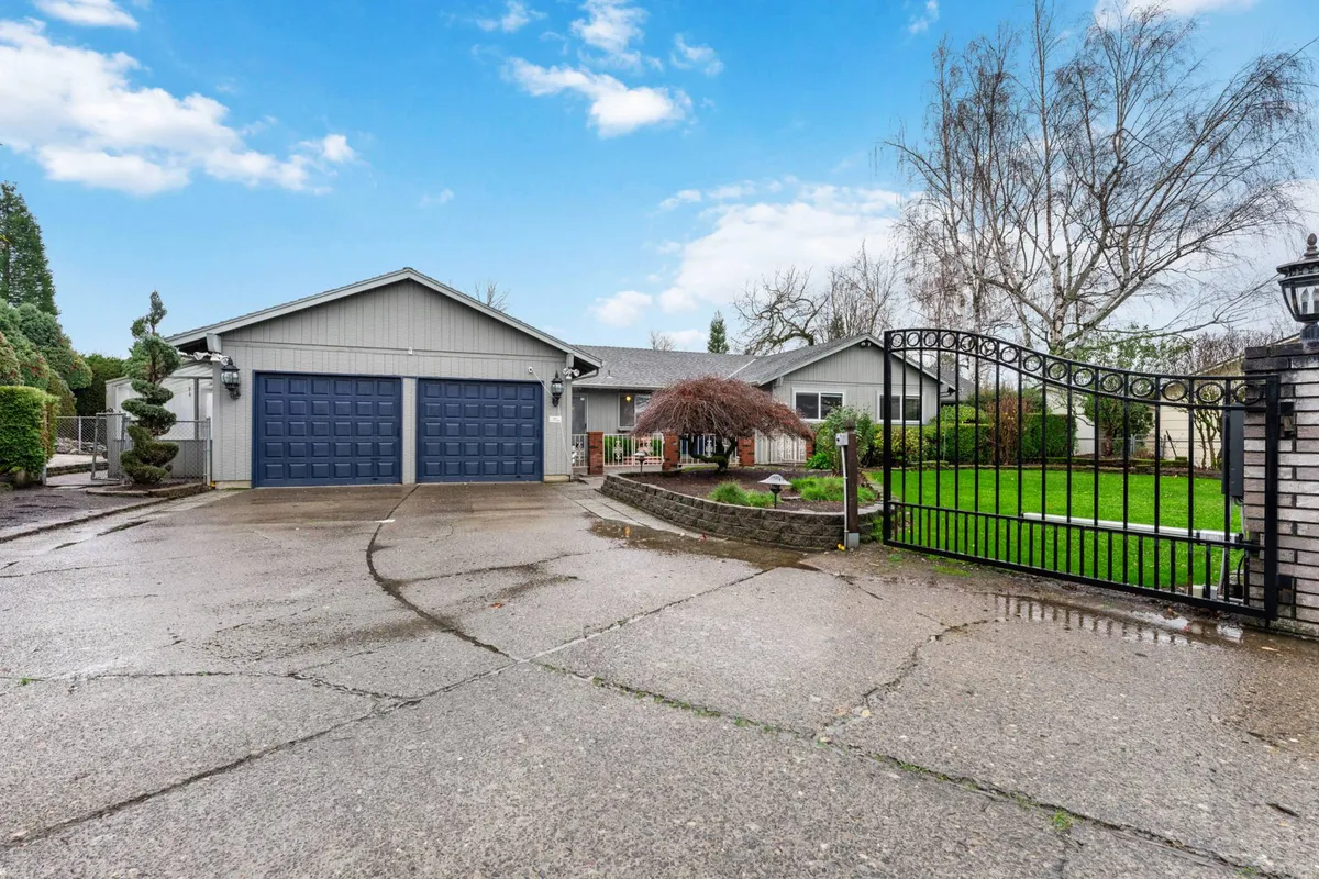This exterior image shows the home's inviting facade with large garage doors, a gated entrance, manicured lawn, and decorative trees. The perspective highlights the outdoor space and suggests proximity to open green areas, which could be reminiscent of a golf course environment.