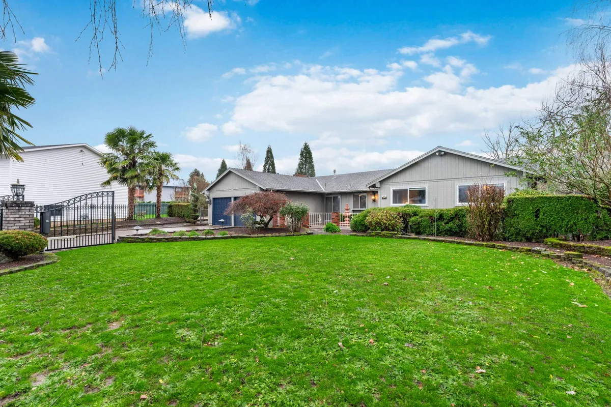 A broad view of the home's inviting facade, showcasing a well-maintained lawn, gated entrance, and landscaped garden beds. The scene projects a sense of tranquility and space, perfect for outdoor relaxation and safe play for kids and pets.