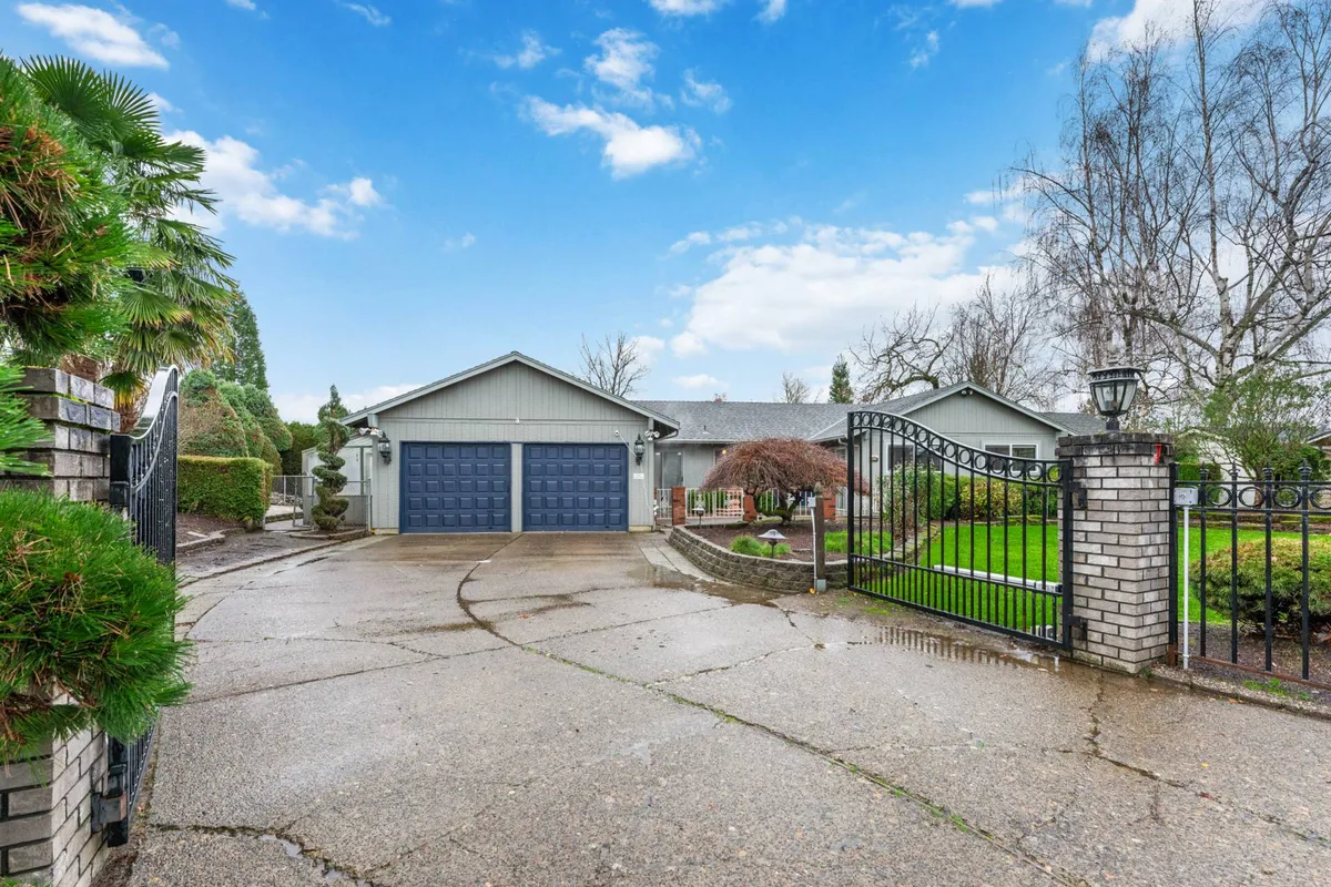 A perspective of the driveway leading to the house, surrounded by a landscaped garden, gated entrance, and garage. The open space allows for outdoor activities and gatherings, enhanced by the warm, inviting atmosphere and visible yard.